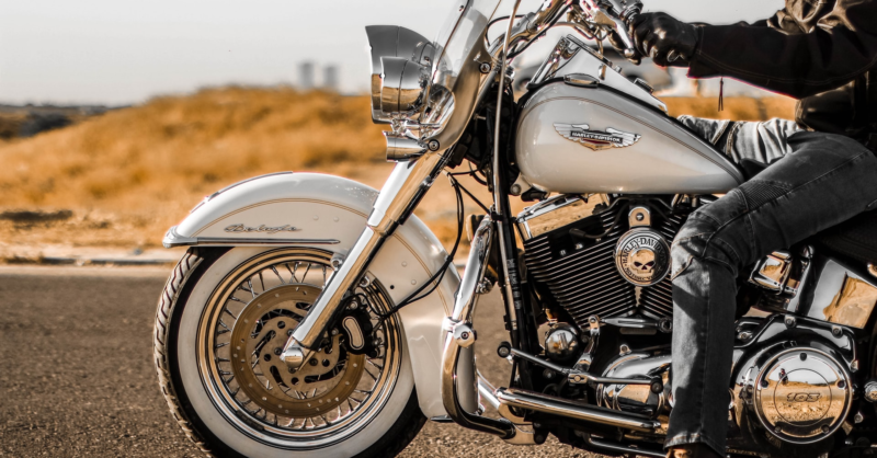 Image shows a Harley Davidson motorcycle up close. Behind the motorcycle is a blurred out view of an American Southwest landscape. Harley Davidson is a leading company with respect to its commitment and effort toward sustainability.